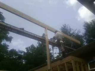 Carpenter setting a ridge beam over a new addition frame — Ice Dam Removal by Roofing Brothers in Rossford