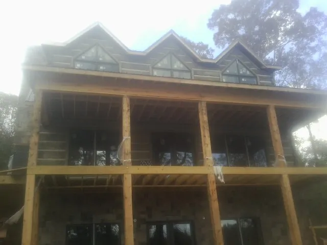 Dormers and porch framing on a large log home under construction — Roof Coating work by our crew in Rossford