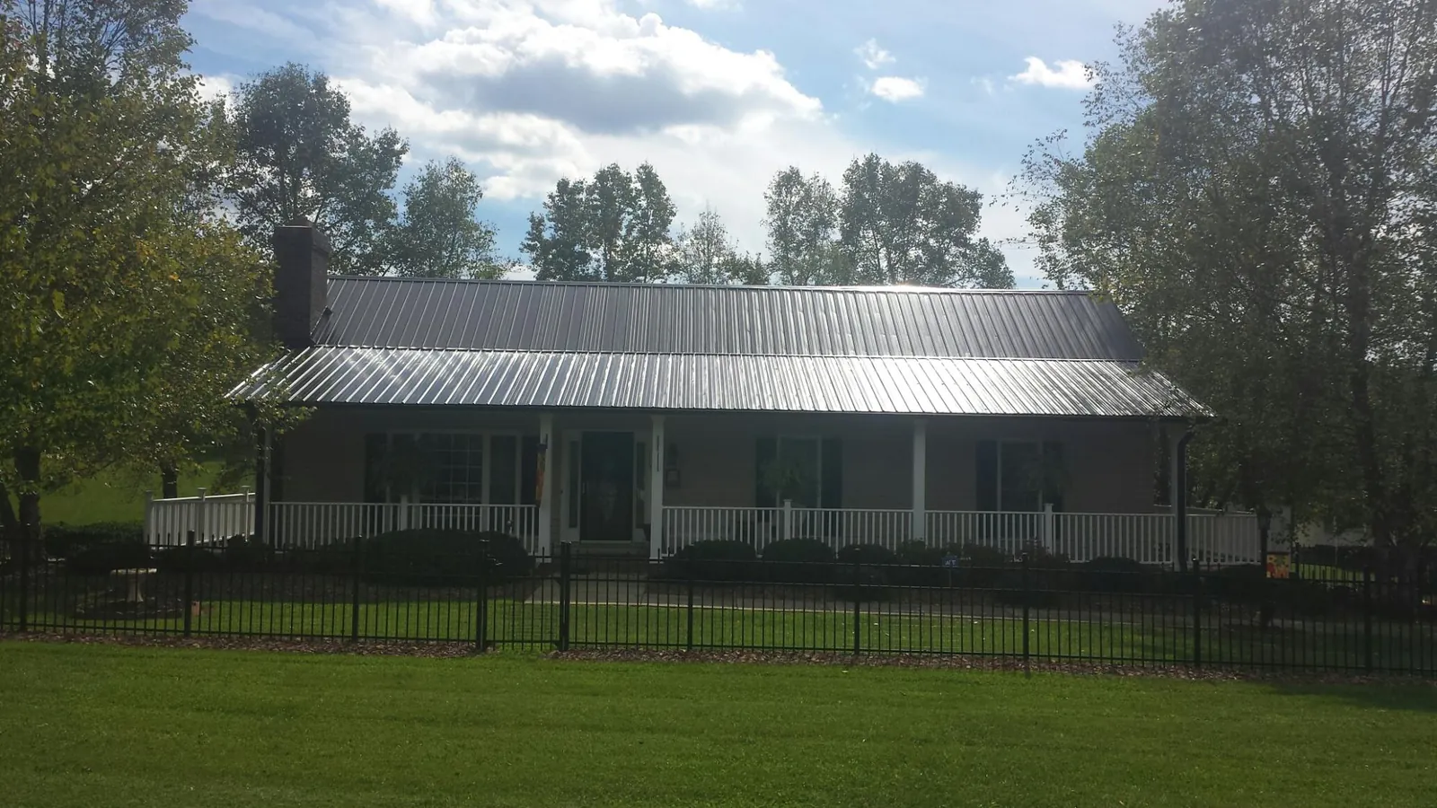 Gray metal roof on a brick ranch with a full width front porch — Gutter Guard Installation work by our crew in Rossford