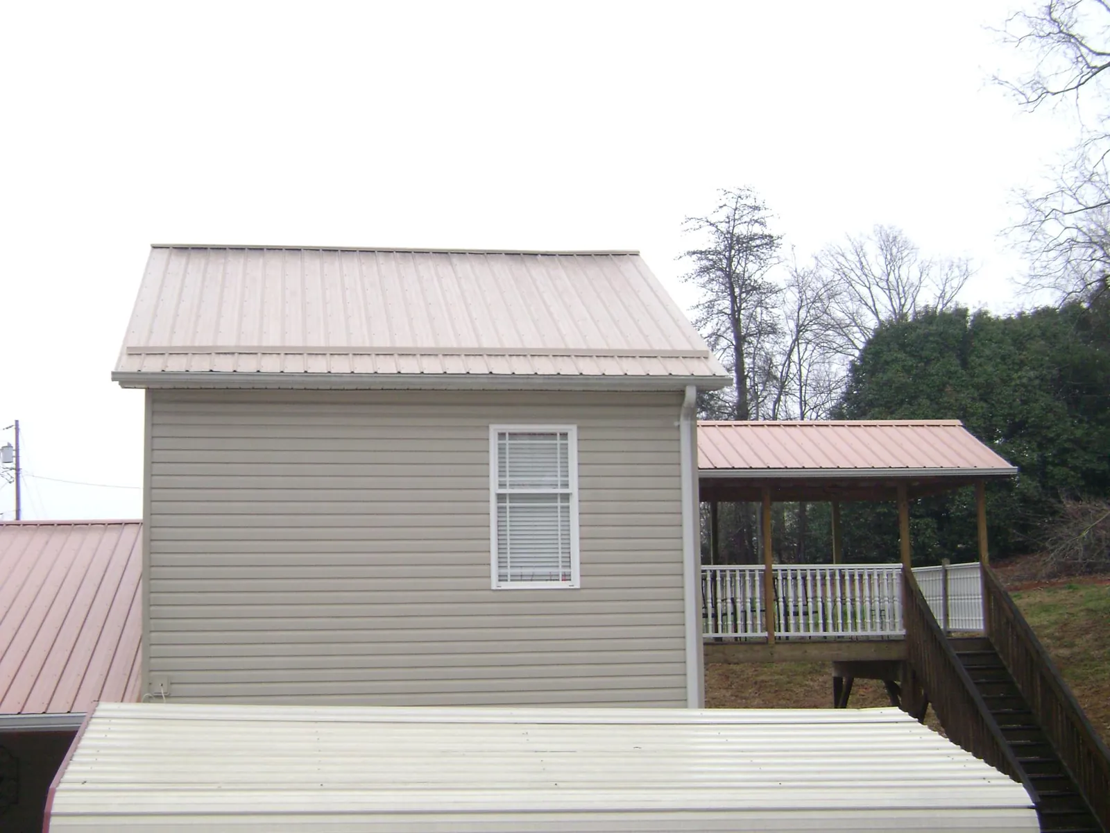 Tan metal roofs on a two story addition and attached porch, from a Roof Replacement job in Rossford