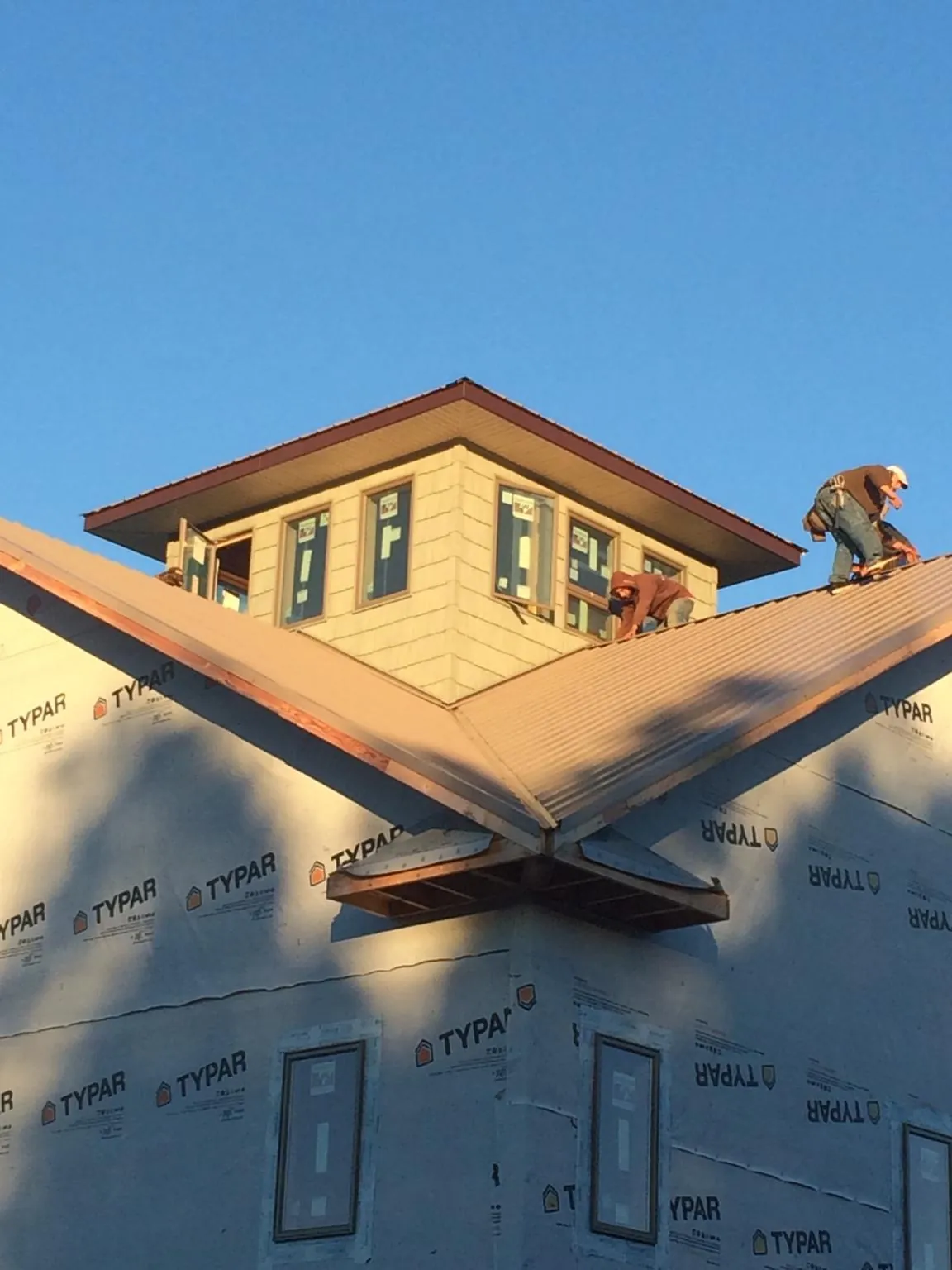 Roofers working around a rooftop cupola on a new metal roof at sunset — Roof Waterproofing in Rossford by Roofing Brothers